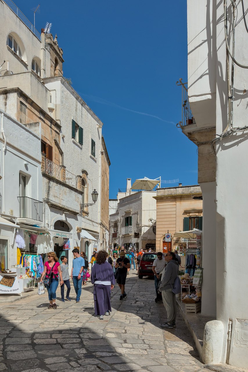 Una via animata del centro storico di Ostuni, fra negozi e passanti